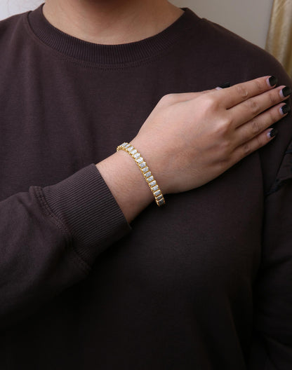 Yellow metal bracelet with white princess shape gemstones in invisible setting, worn on wrist, shot from front angle.