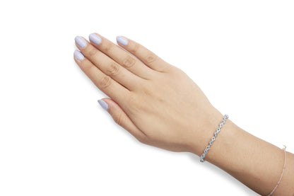Close-up angled shot of a wrist on a model adorned with a white metal bracelet featuring round white gemstones in a prong setting.