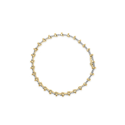 Top-down view of a yellow metal bracelet featuring a row of small round white gemstones in a pave setting.