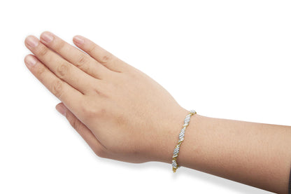 Close-up side view of a yellow metal bracelet with alternating clusters of round white gemstones in prong settings and baguette white gemstones in channel settings, worn on a model's wrist with hand extended and fingers together.