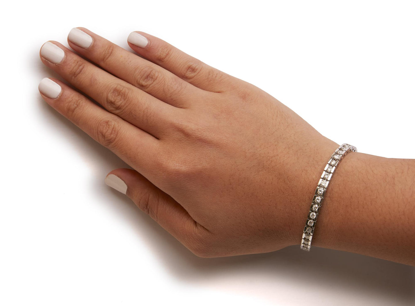 White metal bracelet with round shaped white gemstones in channel setting, worn on a model's wrist, side angle.