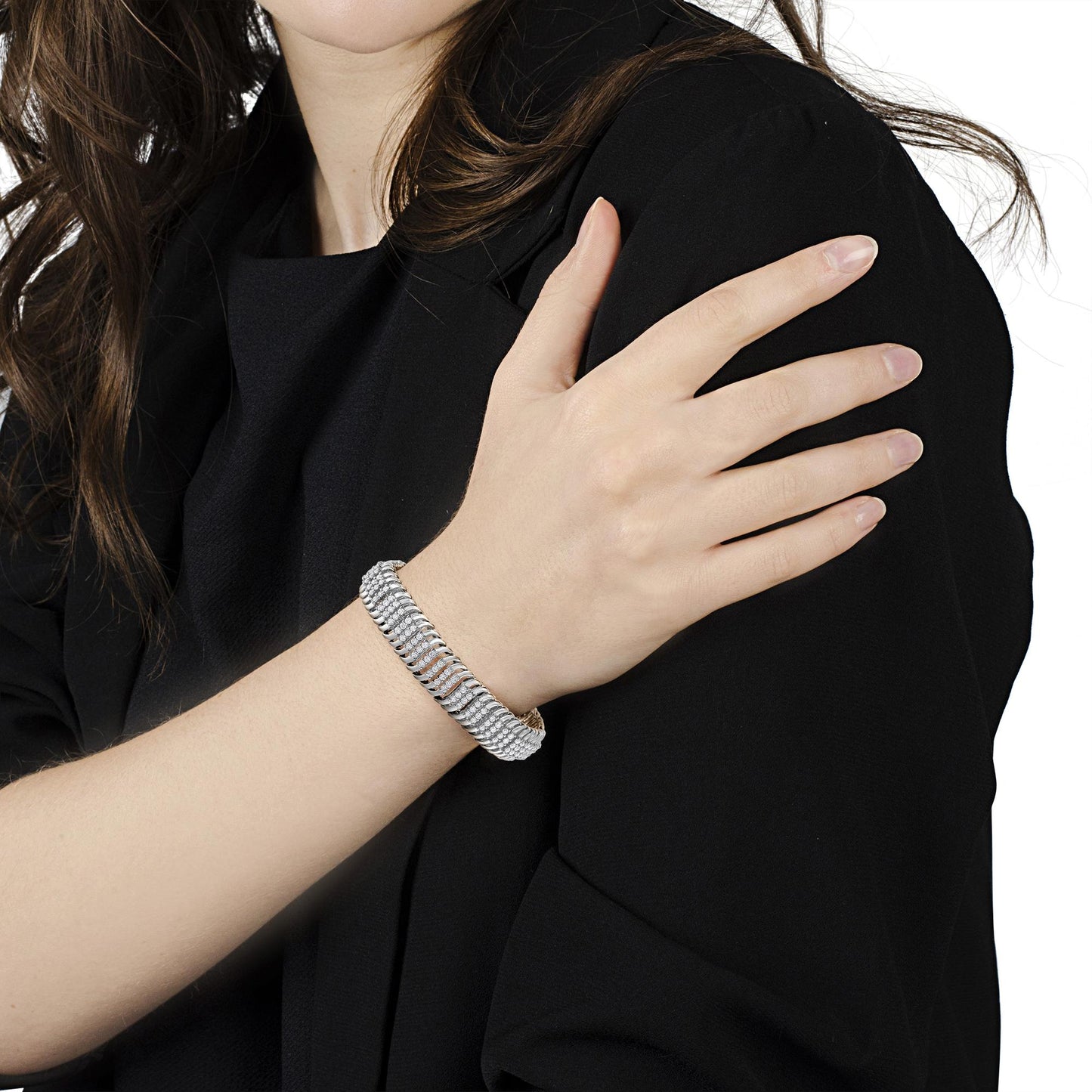 White metal bracelet with multiple rows of round white gemstones in prong settings, worn on a model's wrist, side angle view.
