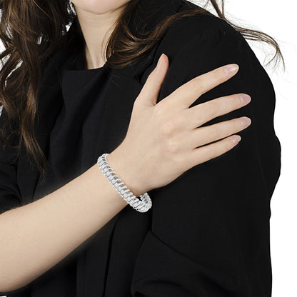 White metal bracelet with princess-shaped white gemstones in invisible setting, worn on model's wrist, angled view.