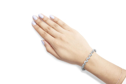 White metal bracelet with alternating round prong-set and baguette channel-set white gemstones, shown on a model's wrist from a top angle.