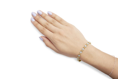 Yellow bracelet with round white gemstones in prong settings, shown on model's wrist from top angle.