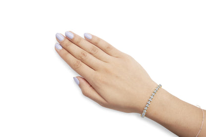 Yellow bracelet with prong-set round white gemstones, worn on wrist, top side view.