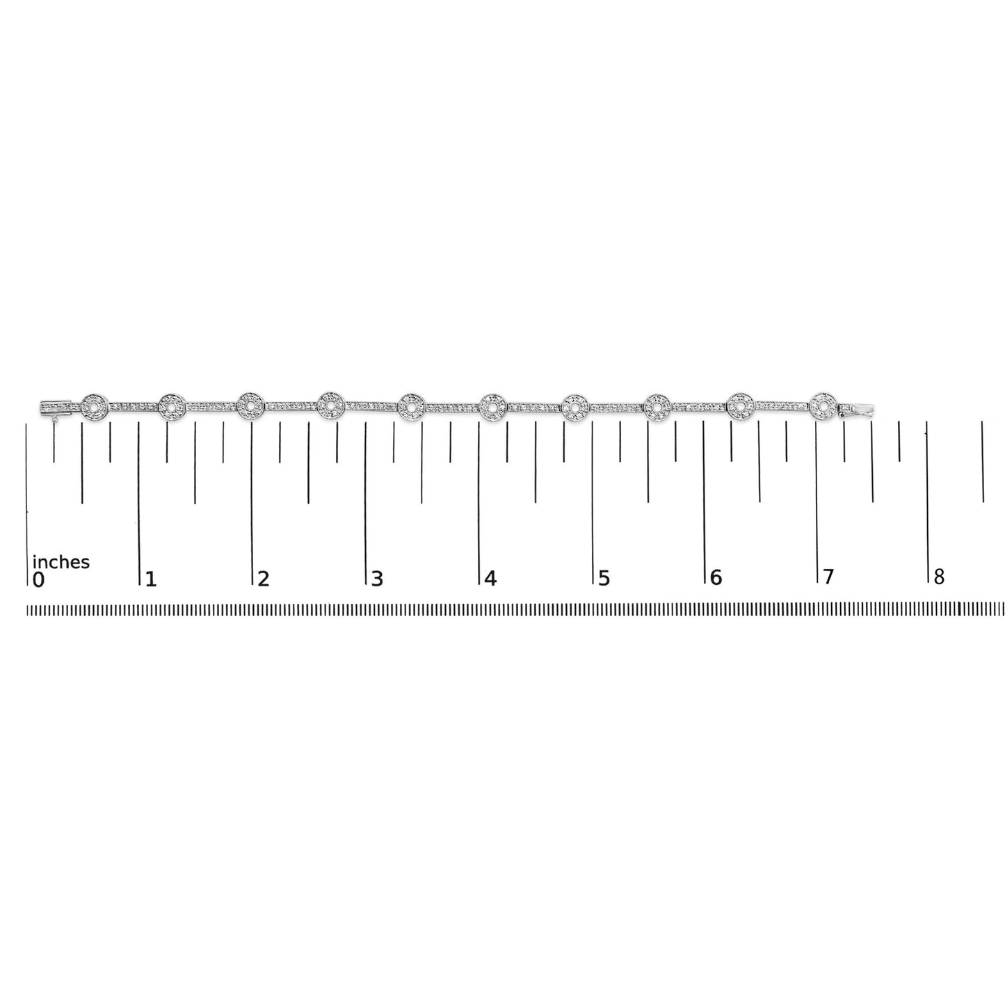 Top-down view of a white metal bracelet with round white gemstones in prong settings, displayed on a ruler for size reference.