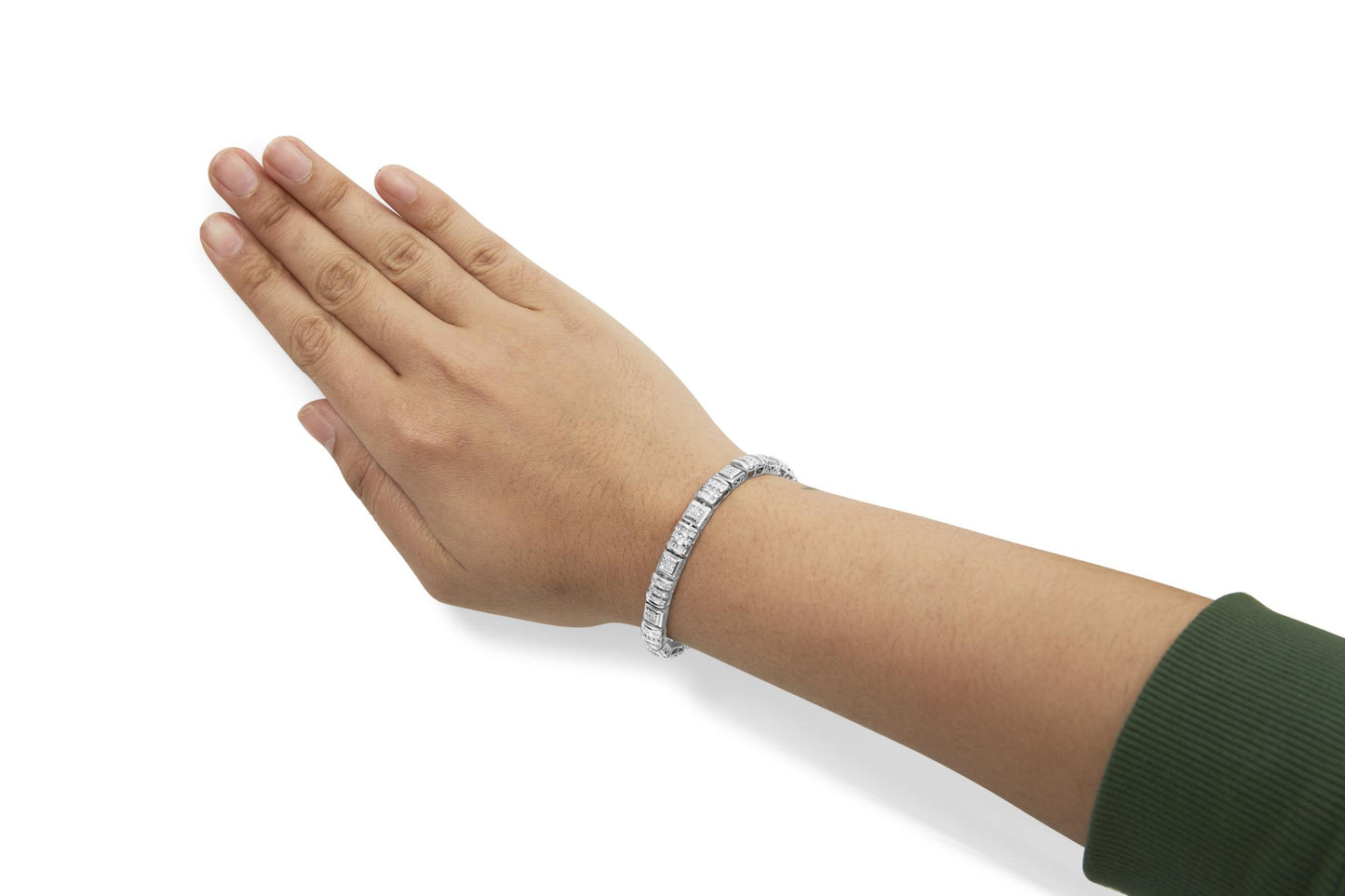 White metal bracelet with round pave set white gemstones alternating with baguette channel set white gemstones, shown on a model's wrist from a top angled view.