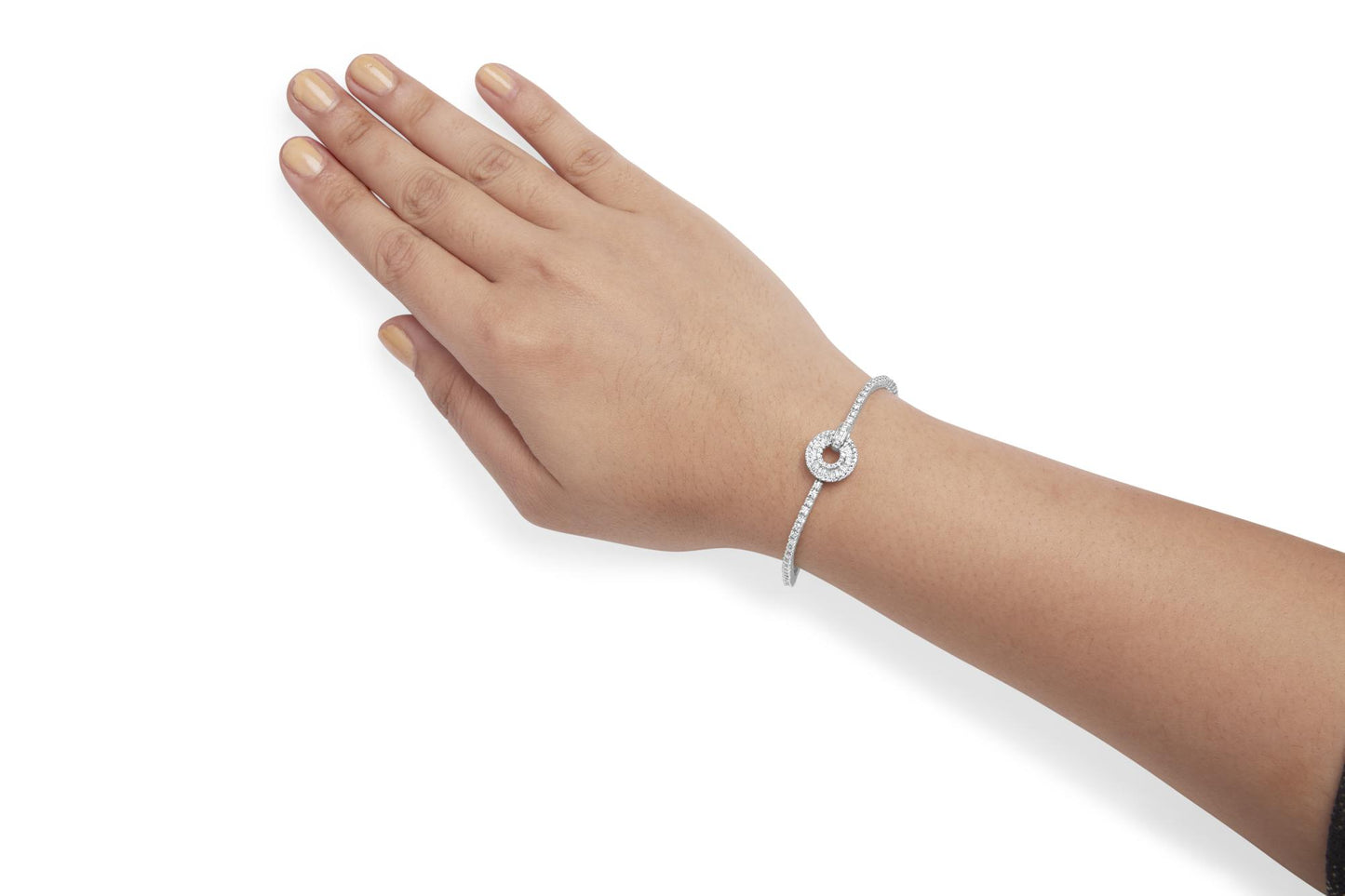 White metal bracelet with round and baguette white gemstones arranged in a circular design, shown on a model's wrist from a top-side angle.