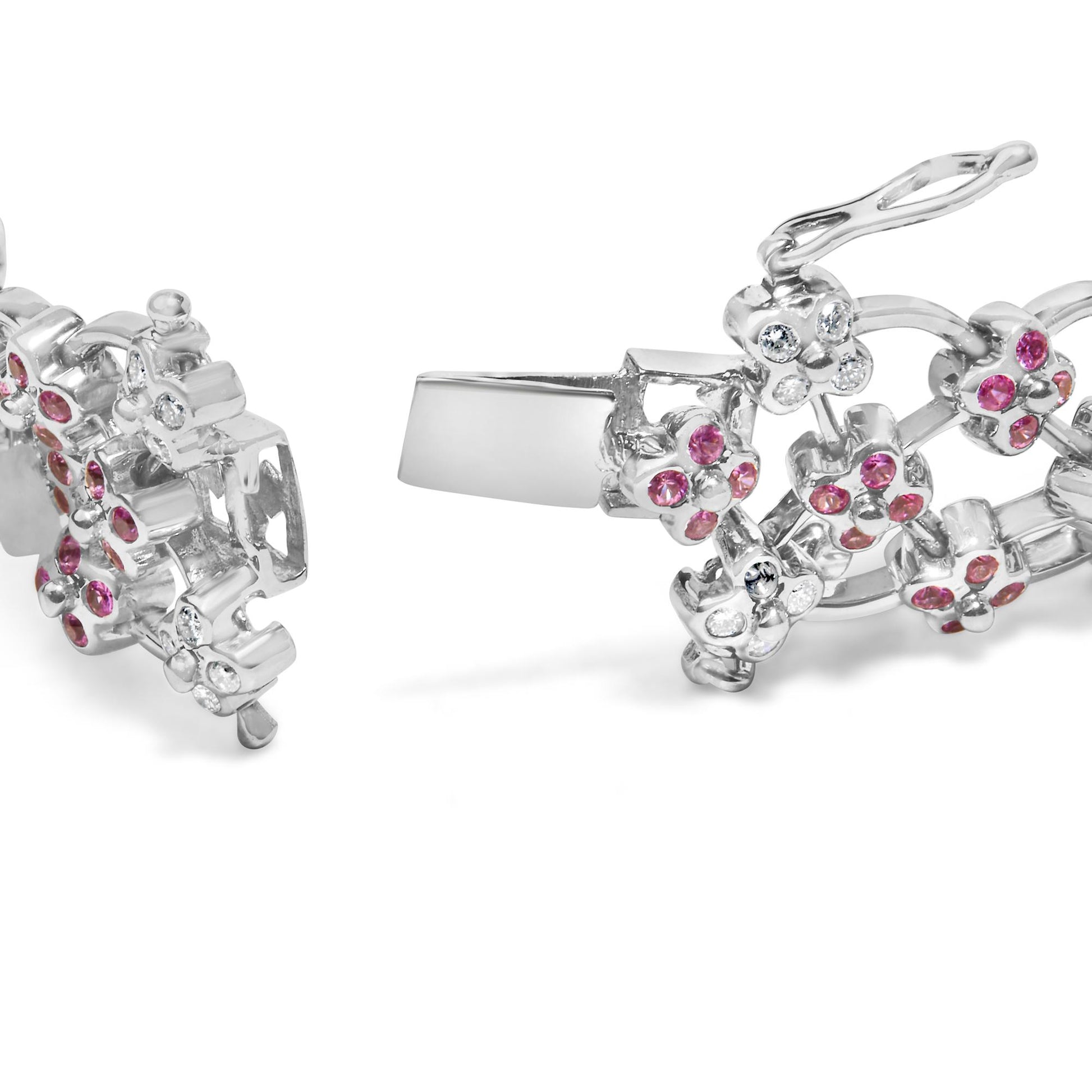 Close-up angled view of a white metal bracelet with floral designs showcasing round pink and white gemstones in bezel settings, with the clasp open.