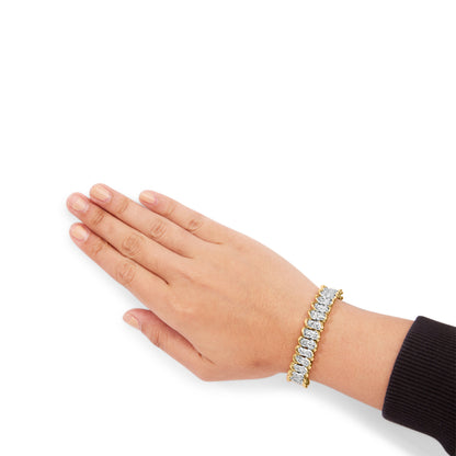 Yellow metal bracelet with white round gemstones set in prongs, shown on a model's wrist from a top angle.