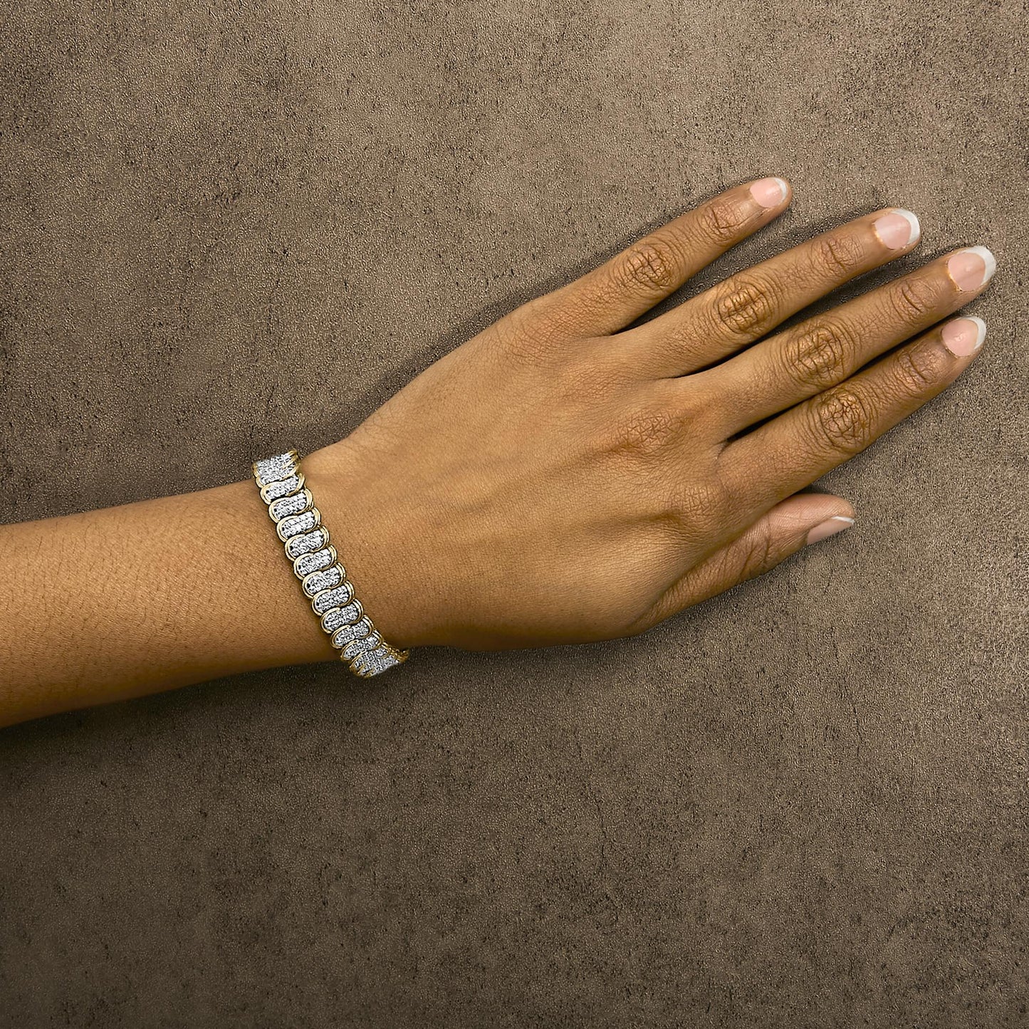 Yellow metal bracelet with white round gemstones in prong settings, shown worn on a model's wrist from a top angle.