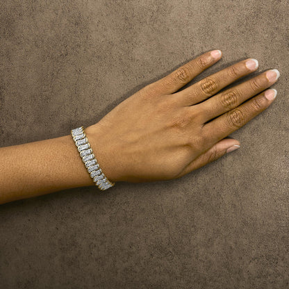 Yellow metal bracelet with white round gemstones in prong settings, shown worn on a model's wrist from a top angle.