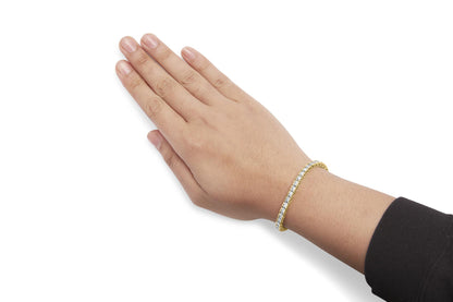 Close-up of a yellow bracelet with white round gemstones in prong settings, worn on a model's wrist, shown from an angled top view.