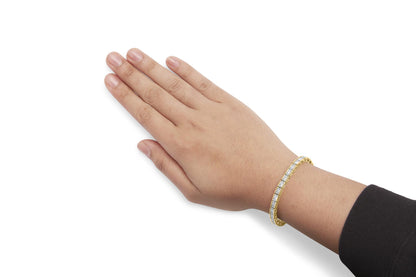 Yellow metal bracelet with channel-set white round gemstones, shown on a model's wrist from a top-side angle.