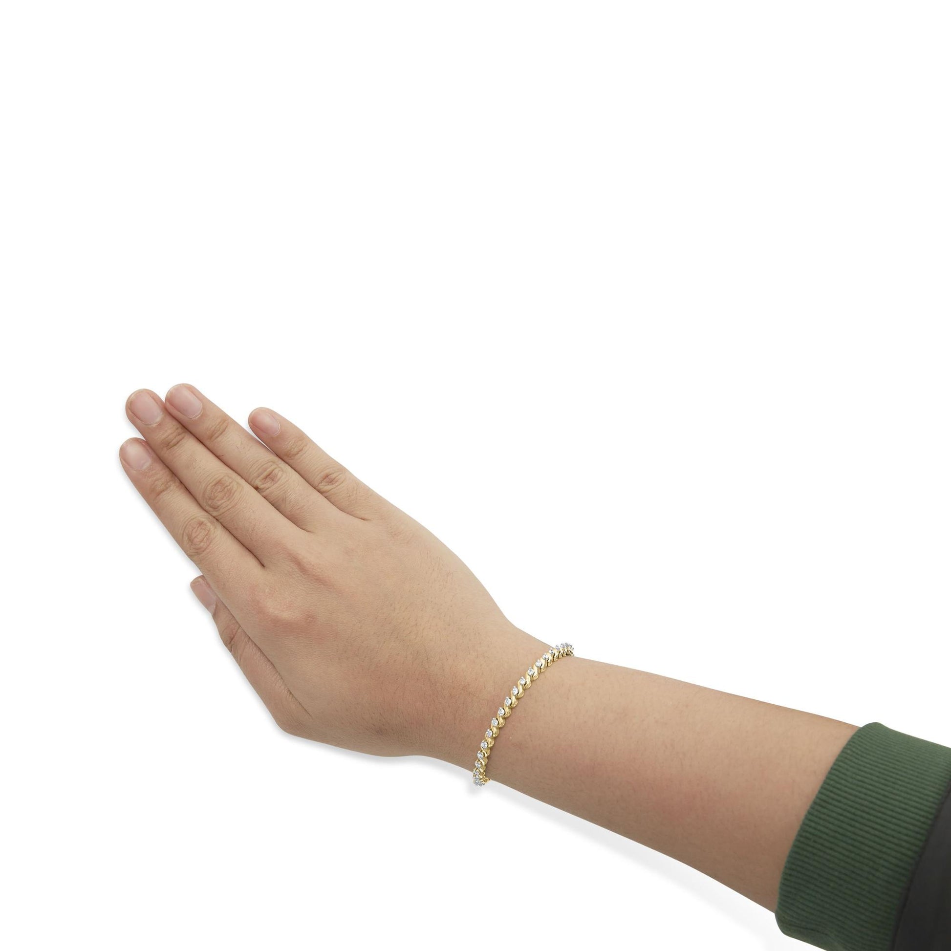 Yellow metal bracelet with white round and baguette gemstones shown worn on a model's wrist, side angle.