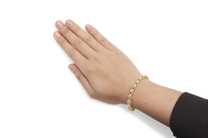 Yellow metal bracelet with round prong-set white gemstones on a model's wrist, side angled view.