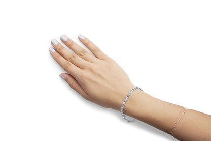 White metal bracelet with alternating round prong-set and baguette channel-set white gemstones, shown on a model's wrist from a top angle.