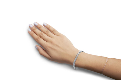 White metal bracelet with round white gemstones in pave setting, shown on a model's wrist from a top angle.