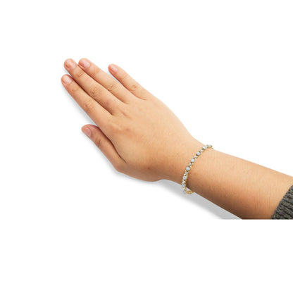 Yellow bracelet with round white gemstones in pave setting, shown on a model's wrist from an angled top view.