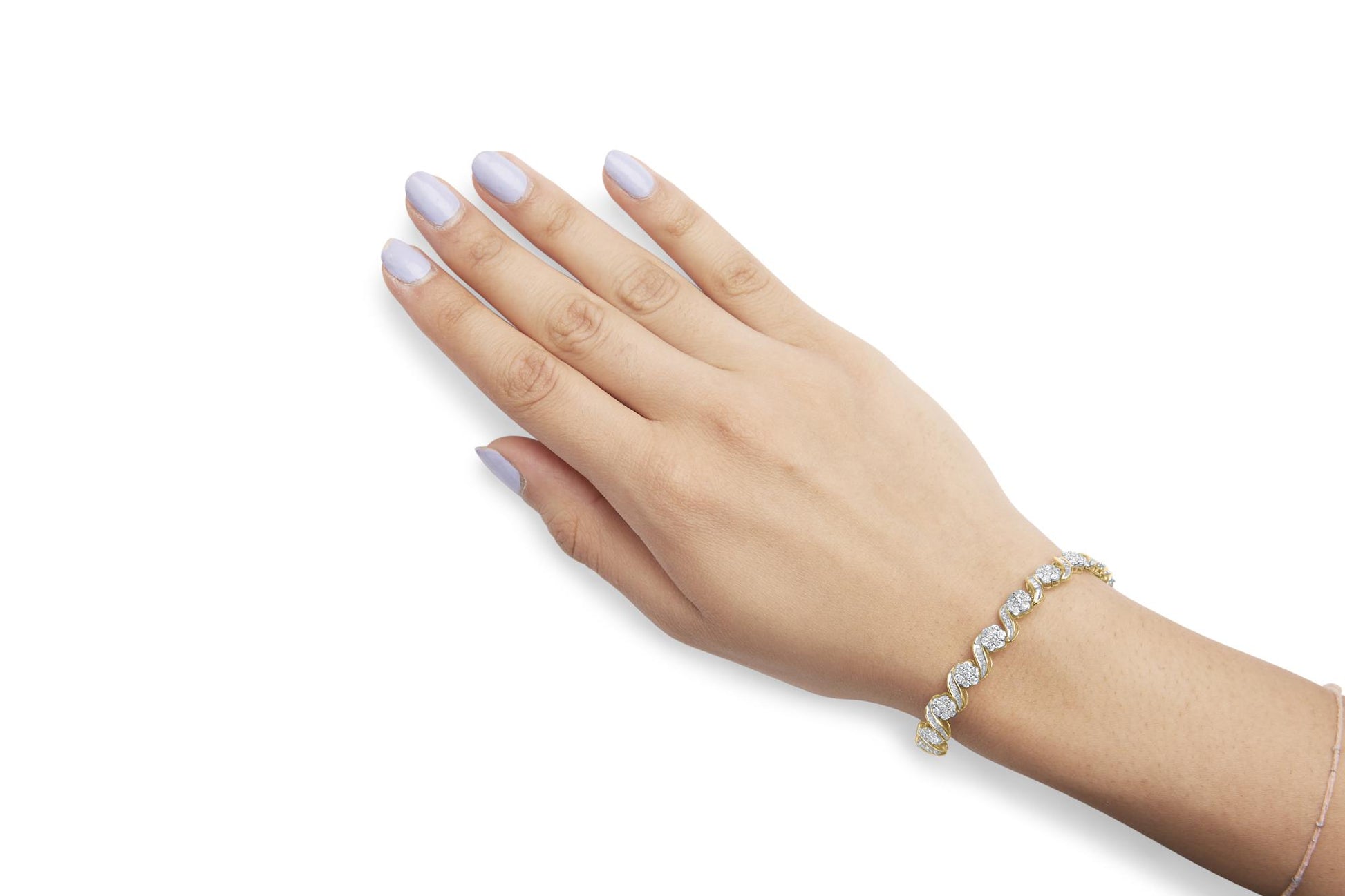 Yellow metal bracelet with round and baguette white gemstones in prong and channel settings, shown on a model's wrist in a top-down angle.