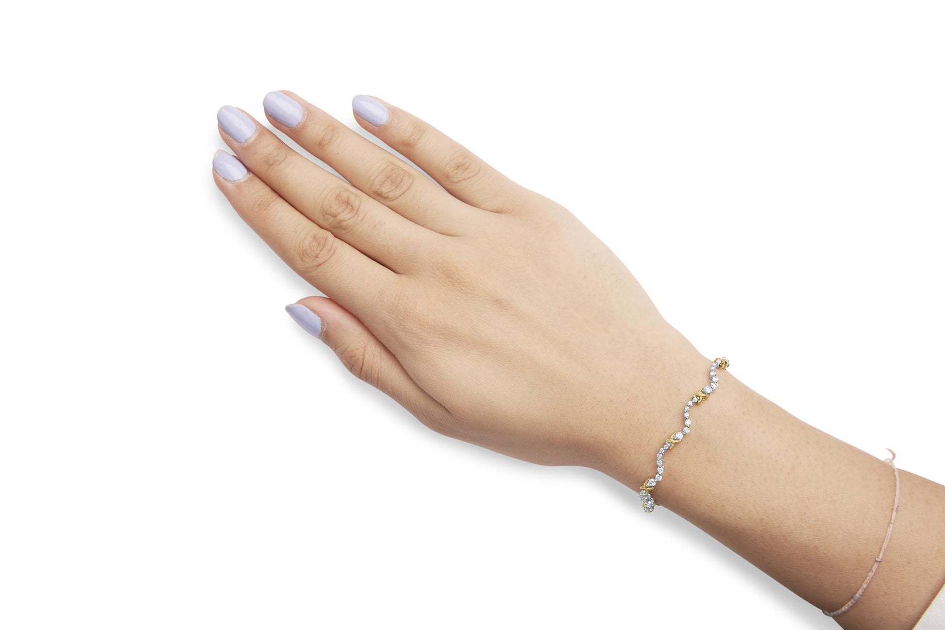 Bracelet with alternating yellow and white metal links set with round white gemstones, worn on a model's wrist, shot from above at an angle.