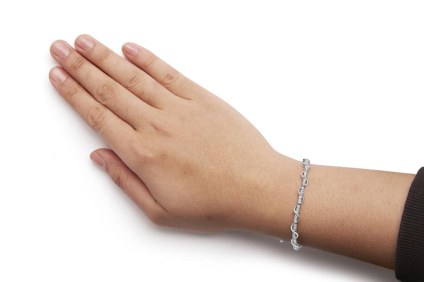 White metal bracelet with round white gemstones in prong settings, shown on a model's wrist from a top angle.