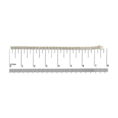 Top view of yellow bracelet with white round prong-set and baguette channel-set gemstones, placed on a ruler for size reference.