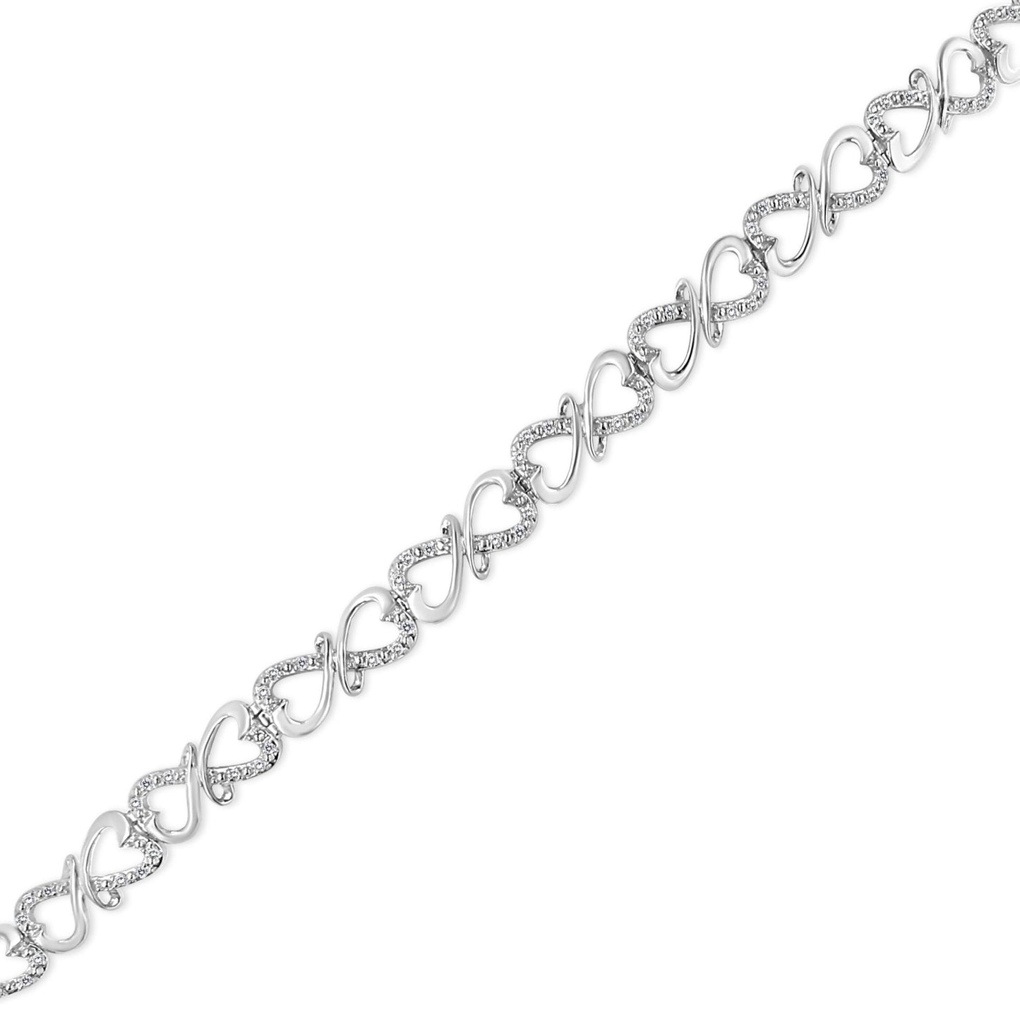 Diagonal close-up of a white metal bracelet featuring alternating heart and infinity symbols adorned with round white gemstones in prong settings.