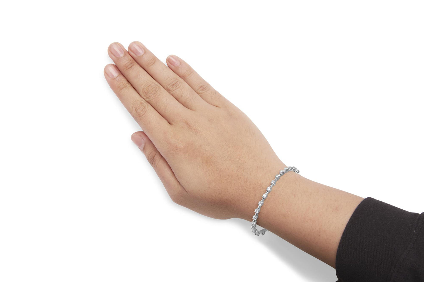 White metal bracelet with round white gemstones in prong settings, shown on a model's wrist from a top-down angle.