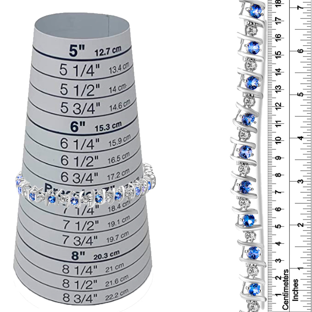 White metal bracelet with alternating round blue and white gemstones in prong settings, shown on a ring sizing cone and next to a ruler for size reference, front and side views.