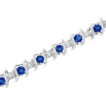 White metal bracelet with alternating round blue and white gemstones in prong and miracle settings, shown at a diagonal angle.