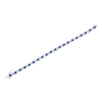 White metal bracelet with alternating round blue gemstones in prong settings and round white gemstones in miracle settings, shown from a top-down angle.
