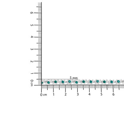 White metal bracelet with alternating round green and white gemstones in prong settings, laid flat on a ruler for size reference, top-down angle.