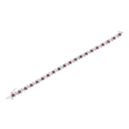 White metal bracelet with alternating round red gemstones in prong settings and round white gemstones in miracle settings, shown at an angle on a white background.