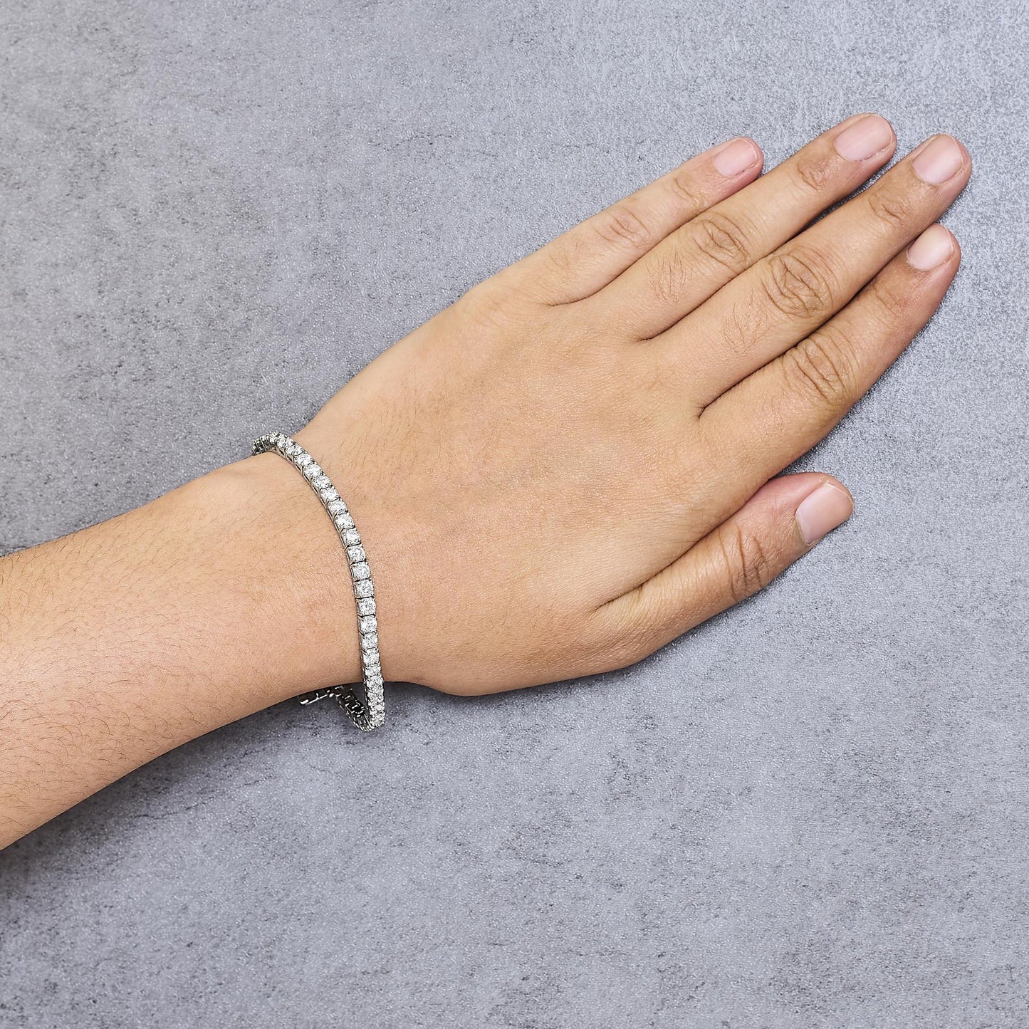 White metal bracelet with prong-set round white gemstones, shown on a wrist from a top-down angle.