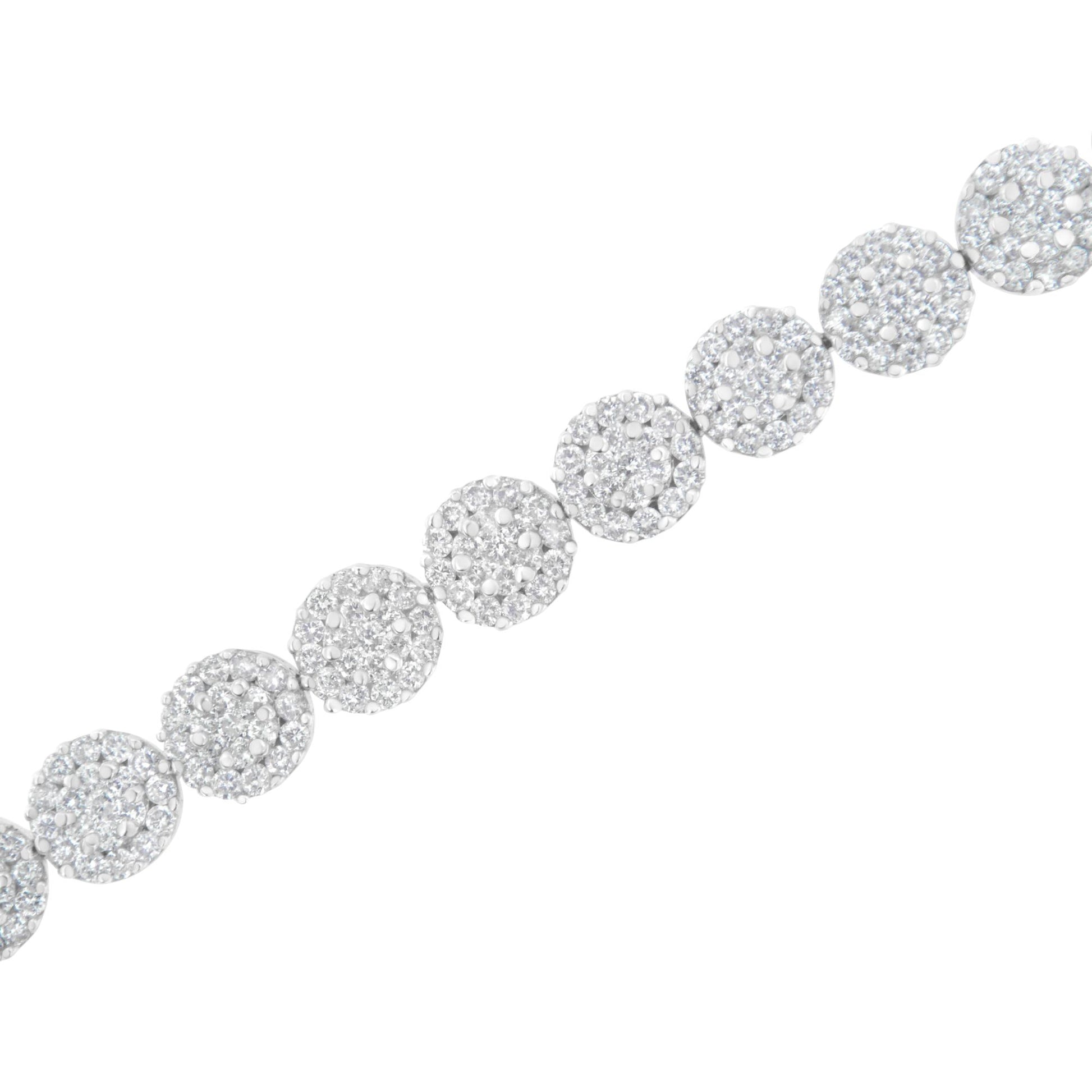 Diagonal close-up of a white metal bracelet with round clusters of white gemstones in prong settings.