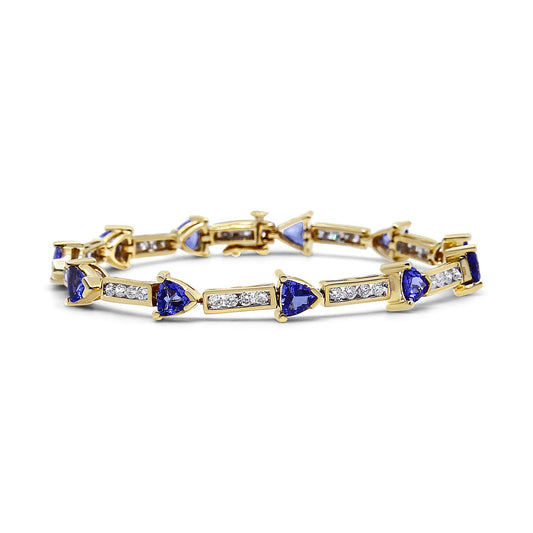 Yellow bracelet with alternating blue trillion-shaped gemstones in prong settings and rectangular sections with channel-set round white gemstones, shown in a front angle view.