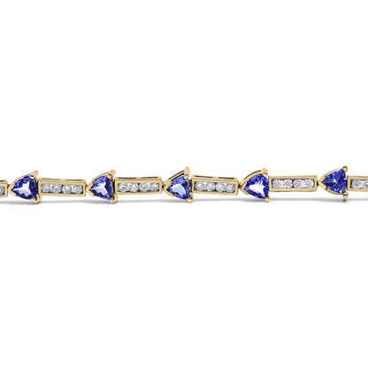 Yellow metal bracelet with alternating blue trillion-shaped gemstones in prong settings and rectangular segments with round white gemstones in channel settings, shown in a close-up horizontal angle.