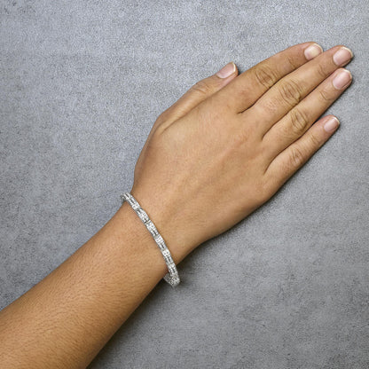 White metal bracelet with channel-set round white gemstones, shown on the wrist from an overhead angle.