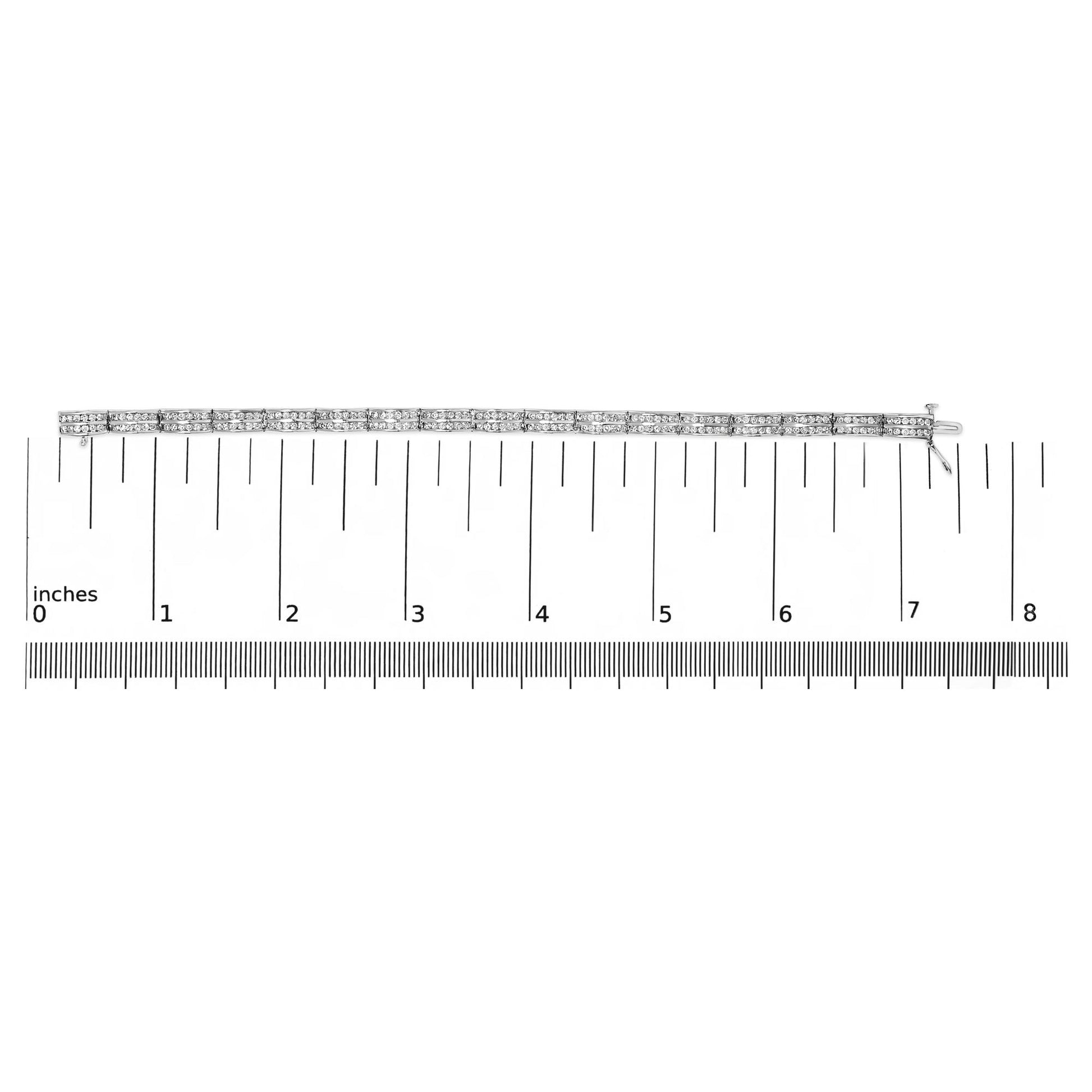 White metal bracelet with two rows of round white gemstones in a channel setting, laid flat on a ruler for size reference, top-down view.