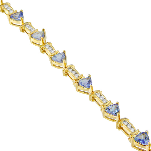 Diagonal close-up of a yellow metal bracelet featuring alternating triangular blue gemstones in prong settings and clusters of round white gemstones in channel settings.
