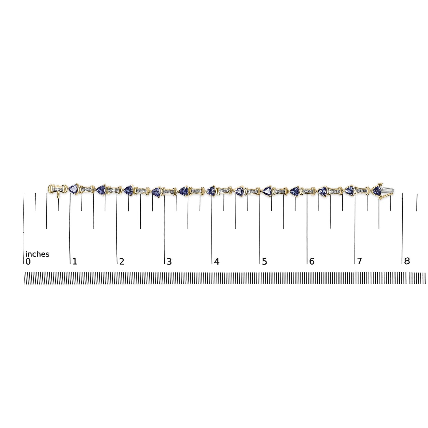 Flat lay image of a yellow metal bracelet with alternating white round gemstones in channel settings and blue trillion-shaped gemstones in prong settings, placed on a ruler for size reference.
