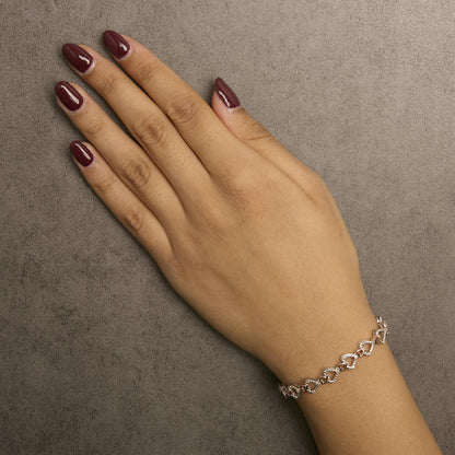 Bracelet with alternating white and rose metal heart links set with small white round pave gemstones, shown worn on a model's wrist in a top-down angle.