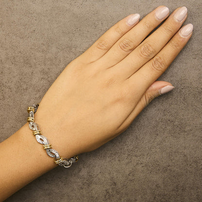 Bracelet with alternating yellow and white metal links accented with white baguette and round gemstones in channel settings, shown worn on a model's wrist from a top-down angle.