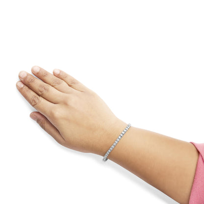 White metal bracelet with round white gemstones in miracle setting, worn on model's wrist, shot from above at an angle.