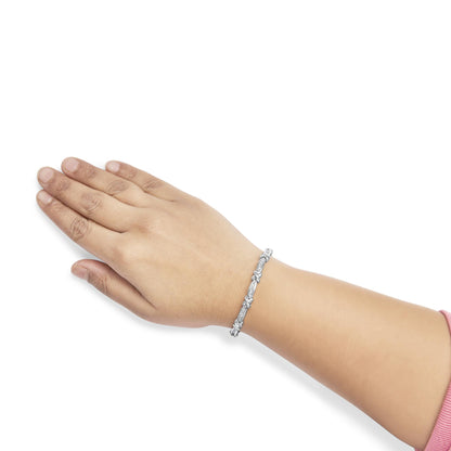 White metal bracelet with baguette shaped white gemstones in channel setting, worn on a model's wrist, shown from a side angle.