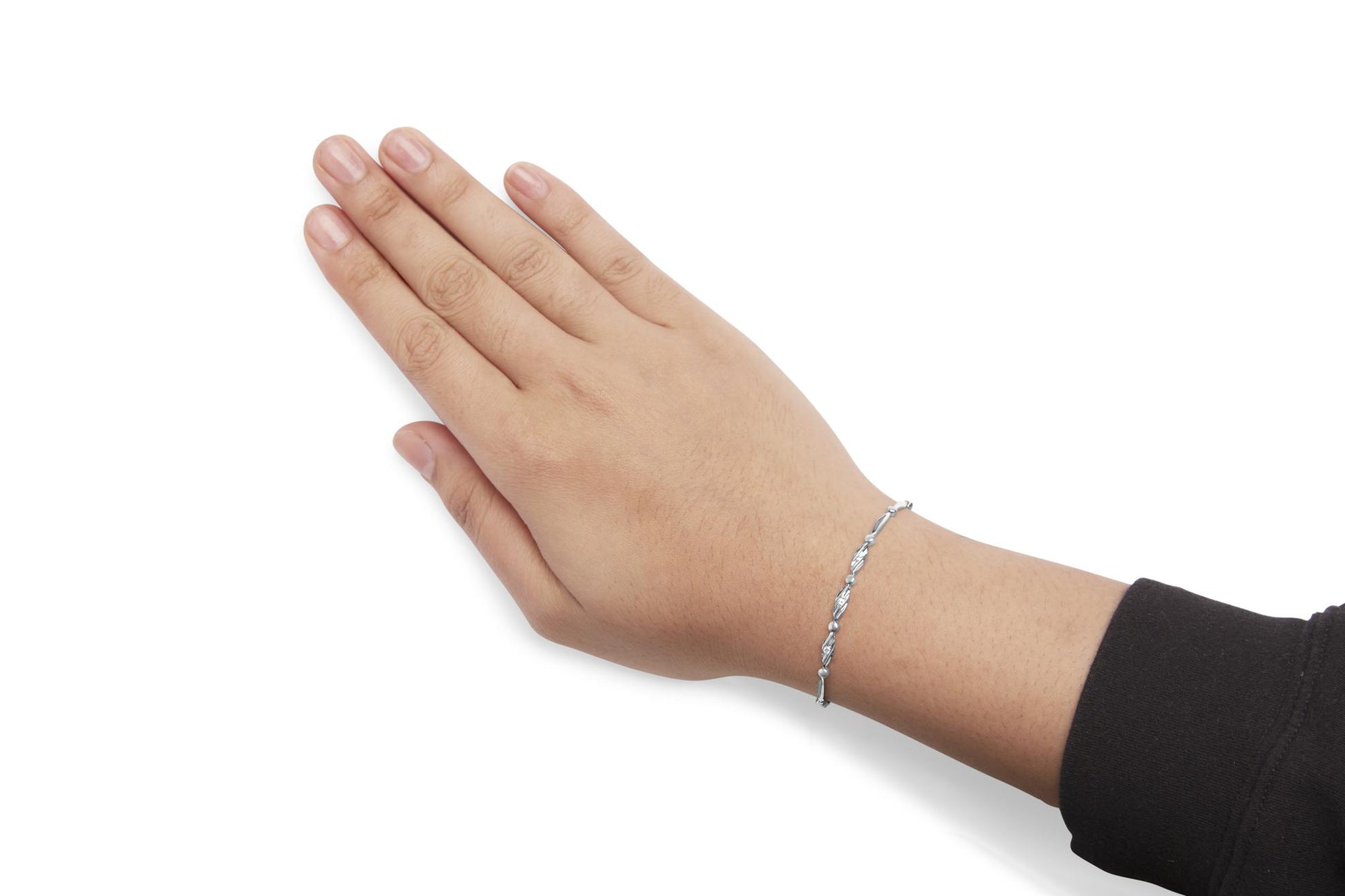 White metal bracelet with alternating elongated and round links, some set with round white gemstones, shown on a model's wrist from a top-down angle.