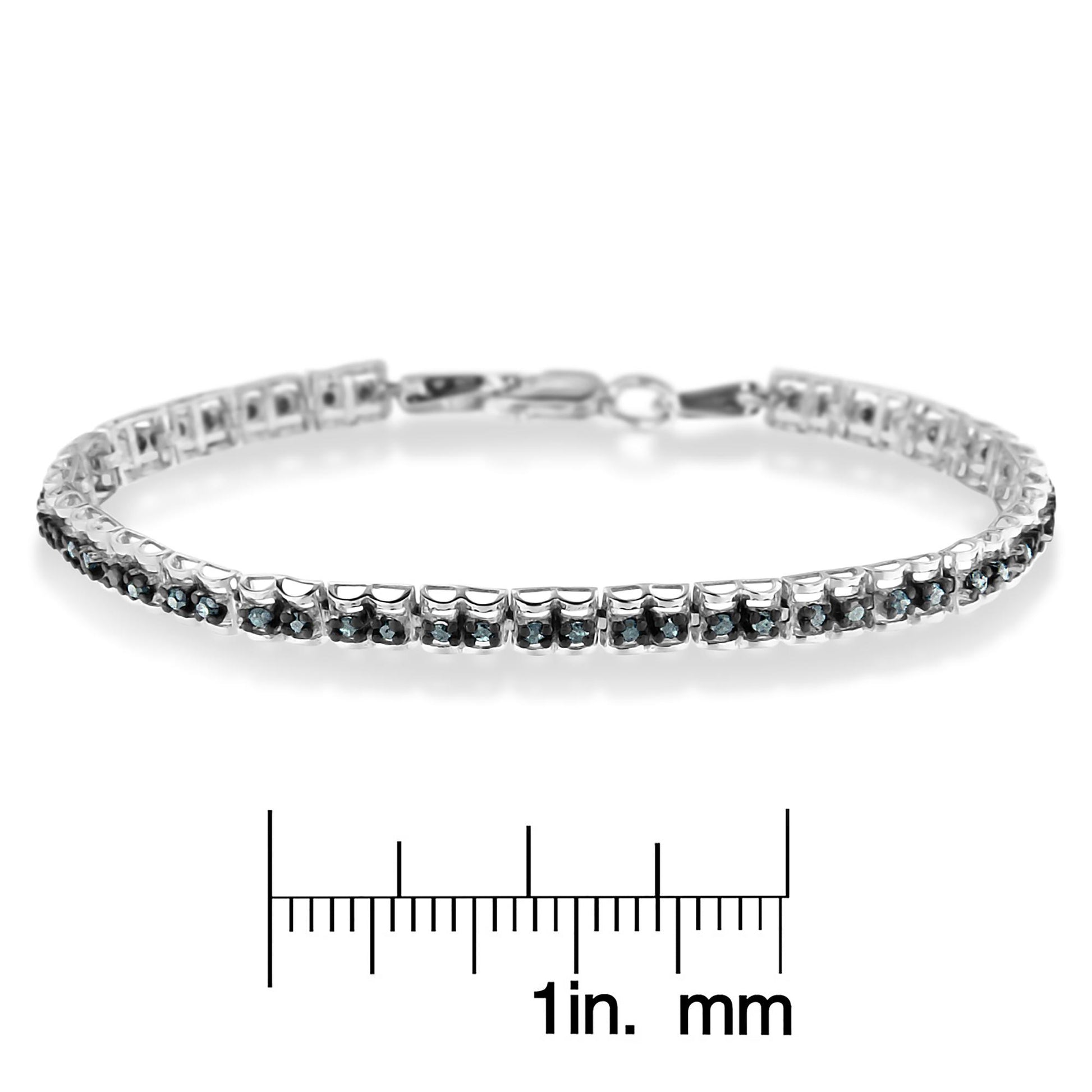 White metal bracelet with round blue gemstones in prong settings, photographed from a side angle, displayed above a ruler for size reference.
