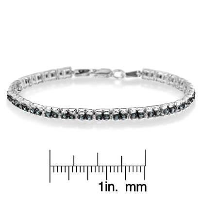 White metal bracelet with round blue gemstones in prong settings, photographed from a side angle, displayed above a ruler for size reference.
